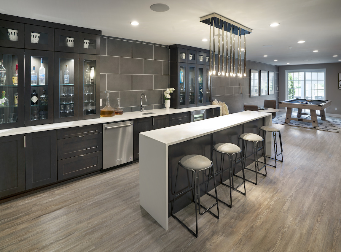 Basement bar highlighted by ample cabinetry, gorgeous lighting, and side pool table